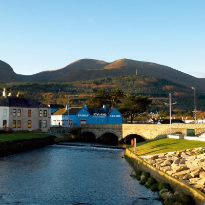 Newcastle,/a> The seaside resort lies on the Irish Sea coast at the base of Slieve Donard, one of the Mourne Mountains, and is known for its sandy beach and the Royal County Down Golf Club.